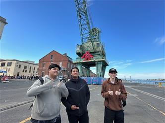 3 students posing in front of a sign