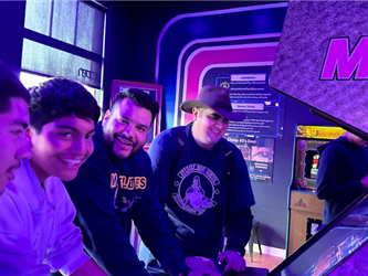 4 people enjoying an arcade cabinet