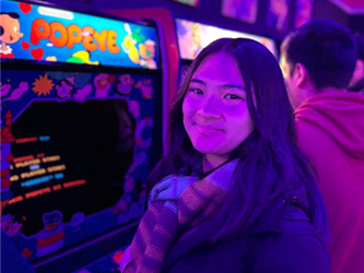 Student in front of a Popeye Arcade Cabinet